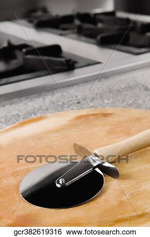Pizza cutter on a cutting board in the kitchen View Large Photo Image Stock Photograph - Pizza cutter on a cutting board in the kitchen. Fotosearch