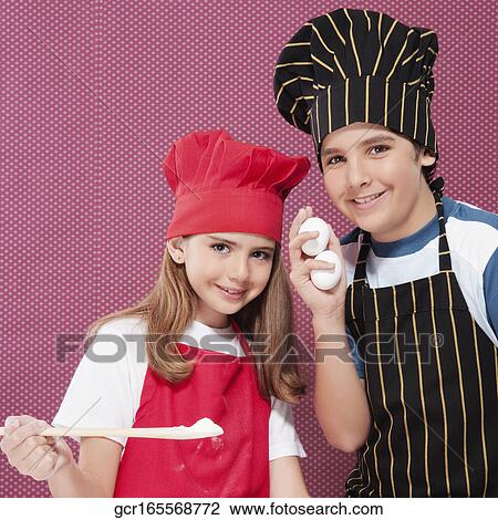 Stock Image - Portrait of a boy and a girl holding flour and eggs. Fotosearch