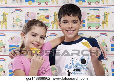 Stock Image - Portrait of a boy and girl eating nachos. Fotosearch