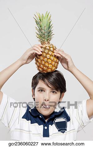 Portrait of a boy carrying a pineapple on his head View Large Photo Image Stock Photo - Portrait of a boy carrying a pineapple on his head. Fotosearch