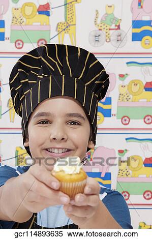 Stock Photography - Portrait of a boy holding a cupcake. Fotosearch