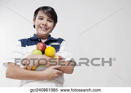 Stock Photography - Portrait of a boy holding fruits. Fotosearch