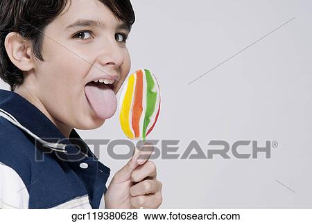 Portrait of a boy licking a lollipop View Large Photo Image Stock Photo - Portrait of a boy licking a lollipop. Fotosearch