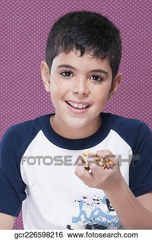 Portrait of a boy with handful of popcorn View Large Photo Image Stock Photograph - Portrait of a boy with handful of popcorn. Fotosearch