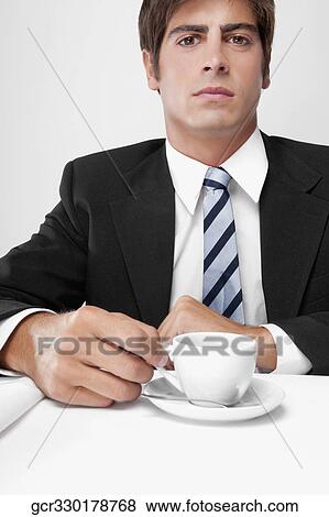 Portrait of a businessman holding a cup of coffee View Large Photo Image Stock Photo - Portrait of a businessman holding a cup of coffee. Fotosearch