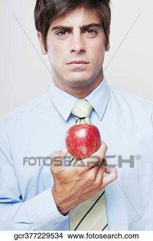 Portrait of a businessman holding a red apple View Large Photo Image Picture - Portrait of a businessman holding a red apple. Fotosearch
