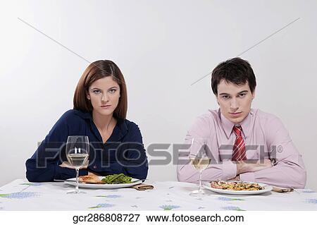 Stock Photo - Portrait of a couple sulking at the dinner table. Fotosearch