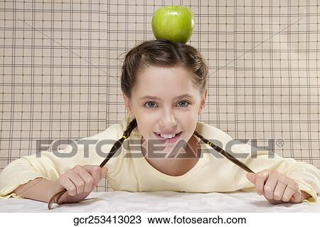 Portrait of a girl balancing a green apple on her head View Large Photo Image Stock Image - Portrait of a girl balancing a green apple on her head. Fotosearch
