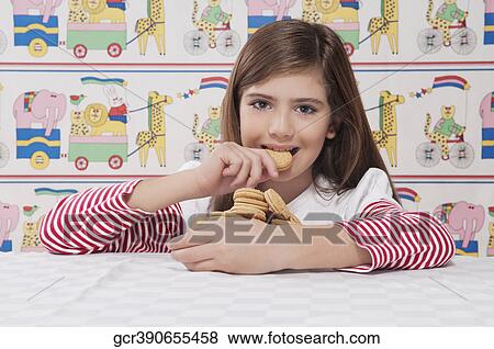 Stock Photo - Portrait of a girl eating a cookie. Fotosearch