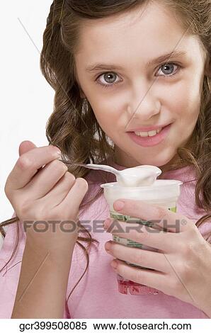 Stock Photography - Portrait of a girl eating a cup of yoghurt. Fotosearch