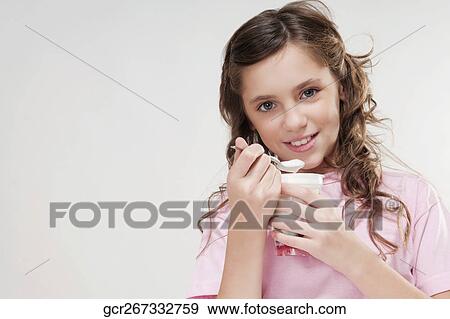Portrait of a girl eating yogurt from a cup View Large Photo Image Stock Photo - Portrait of a girl eating yogurt from a cup. Fotosearch