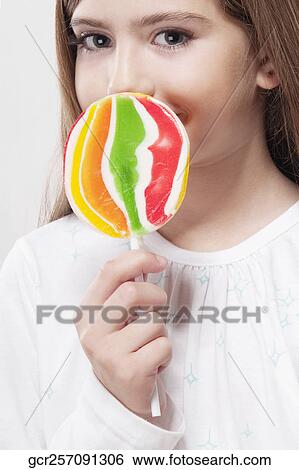 Portrait of a girl holding a lollipop View Large Photo Image Stock Photograph - Portrait of a girl holding a lollipop. Fotosearch