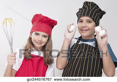 Portrait of a girl holding a wire whisk with her brother showing eggs View Large Photo Image Stock Photo - Portrait of a girl holding a wire whisk with her brother showing eggs. Fotosearch