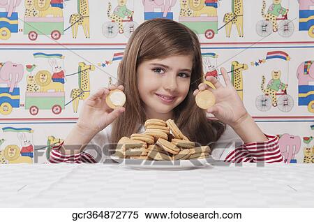 Portrait of a girl holding an open cream cookie View Large Photo Image Stock Photography - Portrait of a girl holding an open cream cookie. Fotosearch