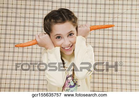 Portrait of a girl holding carrots over her ears View Large Photo Image Stock Photo - Portrait of a girl holding carrots over her ears. Fotosearch