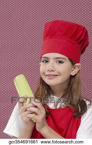Stock Image - Portrait of a girl holding corn on the cob. Fotosearch