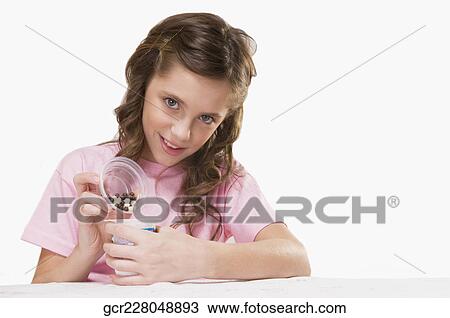 Stock Image - Portrait of a girl opening a cup of yoghurt. Fotosearch