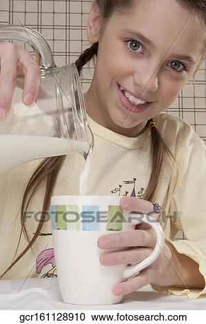 Portrait of a girl pouring milk in a cup View Large Photo Image Stock Image - Portrait of a girl pouring milk in a cup. Fotosearch