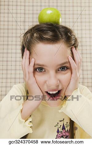 Portrait of a girl with a green apple on her head View Large Photo Image Stock Photo - Portrait of a girl with a green apple on her head. Fotosearch