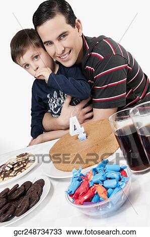 Portrait of a man and his son with a birthday cake in front of them View Large Photo Image Stock Image - Portrait of a man and his son with a birthday cake in front of them. Fotosearch
