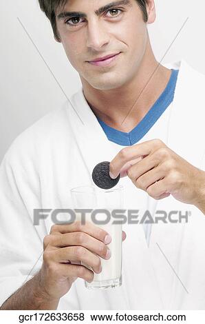 Portrait of a man dunking a cookie in a glass of milk View Large Photo Image Stock Photo - Portrait of a man dunking a cookie in a glass of milk. Fotosearch