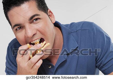 Picture - Portrait of a man eating French fries. Fotosearch