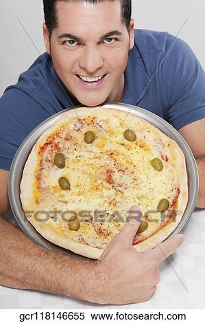 Stock Photography - Portrait of a man holding a pizza pie. Fotosearch