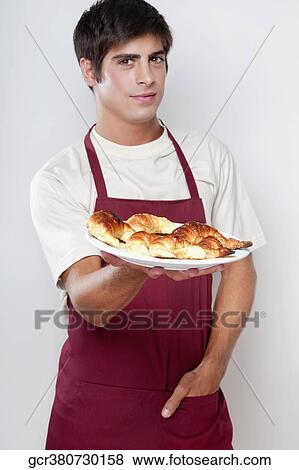 Stock Photo - Portrait of a man holding croissants on a plate. Fotosearch