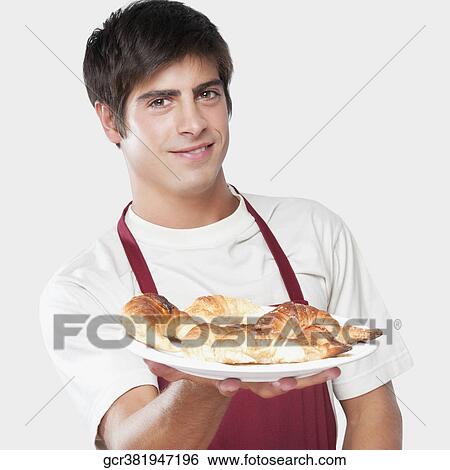 Portrait of a man holding croissants on a plate View Large Photo Image Stock Photograph - Portrait of a man holding croissants on a plate. Fotosearch