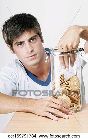 Portrait of a man reaching into a jar of cookies View Large Photo Image Picture - Portrait of a man reaching into a jar of cookies. Fotosearch