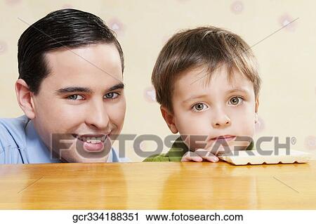 Portrait of a man with his son holding a chocolate bar View Large Photo Image Stock Image - Portrait of a man with his son holding a chocolate bar. Fotosearch