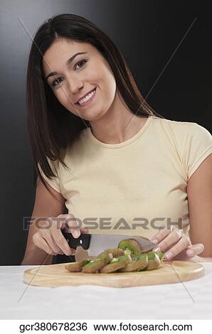 Portrait of a woman cutting kiwi fruit View Large Photo Image Stock Photograph - Portrait of a woman cutting kiwi fruit. Fotosearch