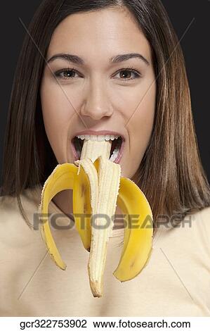 Stock Image - Portrait of a woman eating a banana. Fotosearch