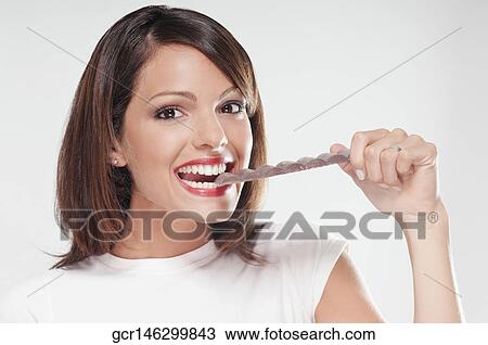 Stock Image - Portrait of a woman eating a bar of chocolate. Fotosearch