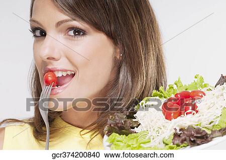 Portrait of a woman eating a cherry tomato View Large Photo Image Stock Image - Portrait of a woman eating a cherry tomato. Fotosearch