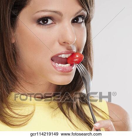 Portrait of a woman eating a cherry tomato with a fork View Large Photo Image Stock Photo - Portrait of a woman eating a cherry tomato with a fork. Fotosearch