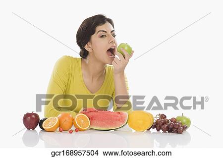 Picture - Portrait of a woman eating a green apple. Fotosearch