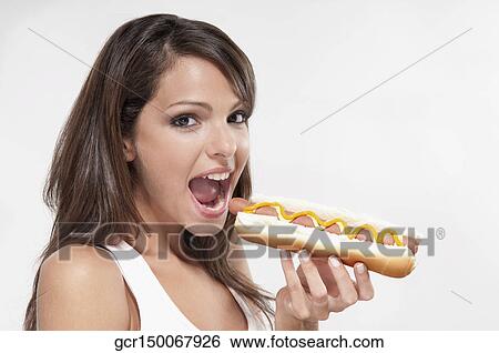 Stock Photograph - Portrait of a woman eating a hot dog. Fotosearch