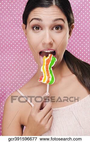 Portrait of a woman eating a lollipop View Large Photo Image Stock Photo - Portrait of a woman eating a lollipop. Fotosearch