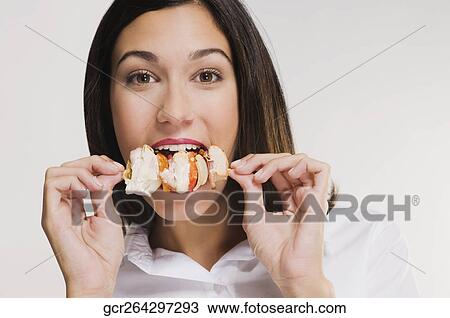 Stock Image - Portrait of a woman eating a shish kebab. Fotosearch