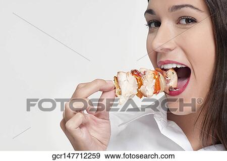 Portrait of a woman eating a shish kebab View Large Photo Image Stock Photo - Portrait of a woman eating a shish kebab. Fotosearch