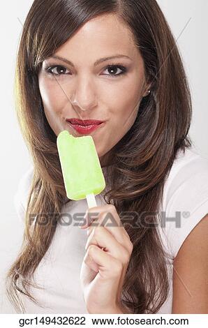 Stock Image - Portrait of a woman eating an ice lolly. Fotosearch