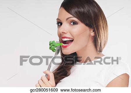 Portrait of a woman eating broccoli with a fork View Large Photo Image Stock Photo - Portrait of a woman eating broccoli with a fork. Fotosearch