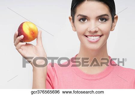 Stock Photograph - Portrait of a woman holding a peach. Fotosearch