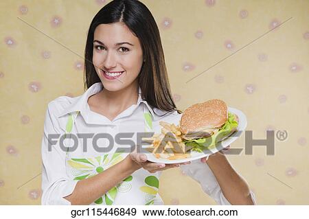 Portrait of a woman holding a plate of burger and fries View Large Photo Image Stock Photo - Portrait of a woman holding a plate of burger and fries. Fotosearch