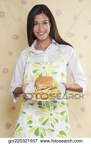 Portrait of a woman holding a plate of burger and fries View Large Photo Image Stock Photo - Portrait of a woman holding a plate of burger and fries. Fotosearch