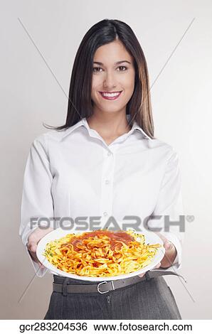 Stock Photograph - Portrait of a woman holding a platter of pasta. Fotosearch