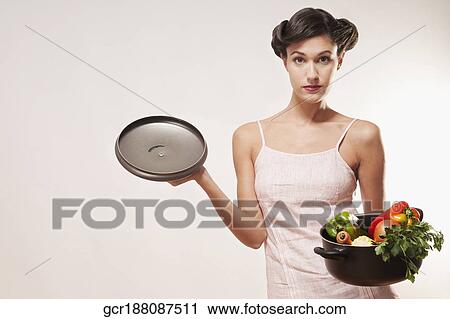 Stock Image - Portrait of a woman holding a pot of fresh vegetables. Fotosearch