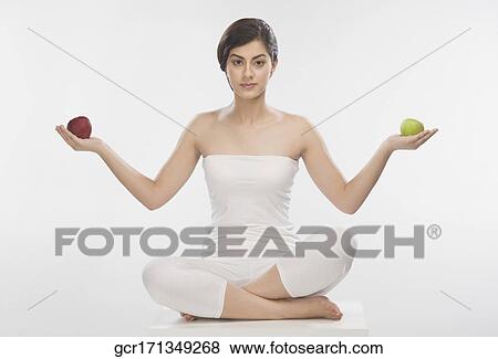 Stock Photo - Portrait of a woman holding a red and a green apple. Fotosearch