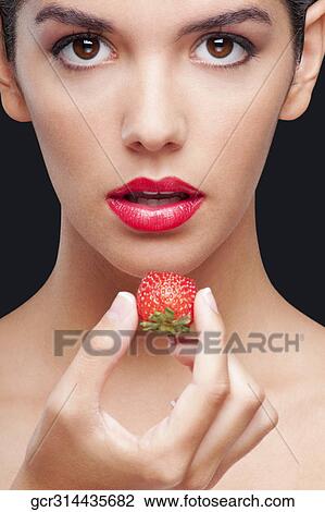 Stock Image - Portrait of a woman holding a strawberry. Fotosearch